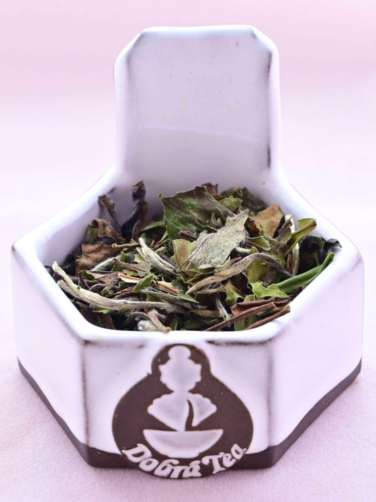 A close-up of Bai Mu Dan leaves. They are large and flat, and mostly green in color with a slight brown tint. They are crisp and brittle.