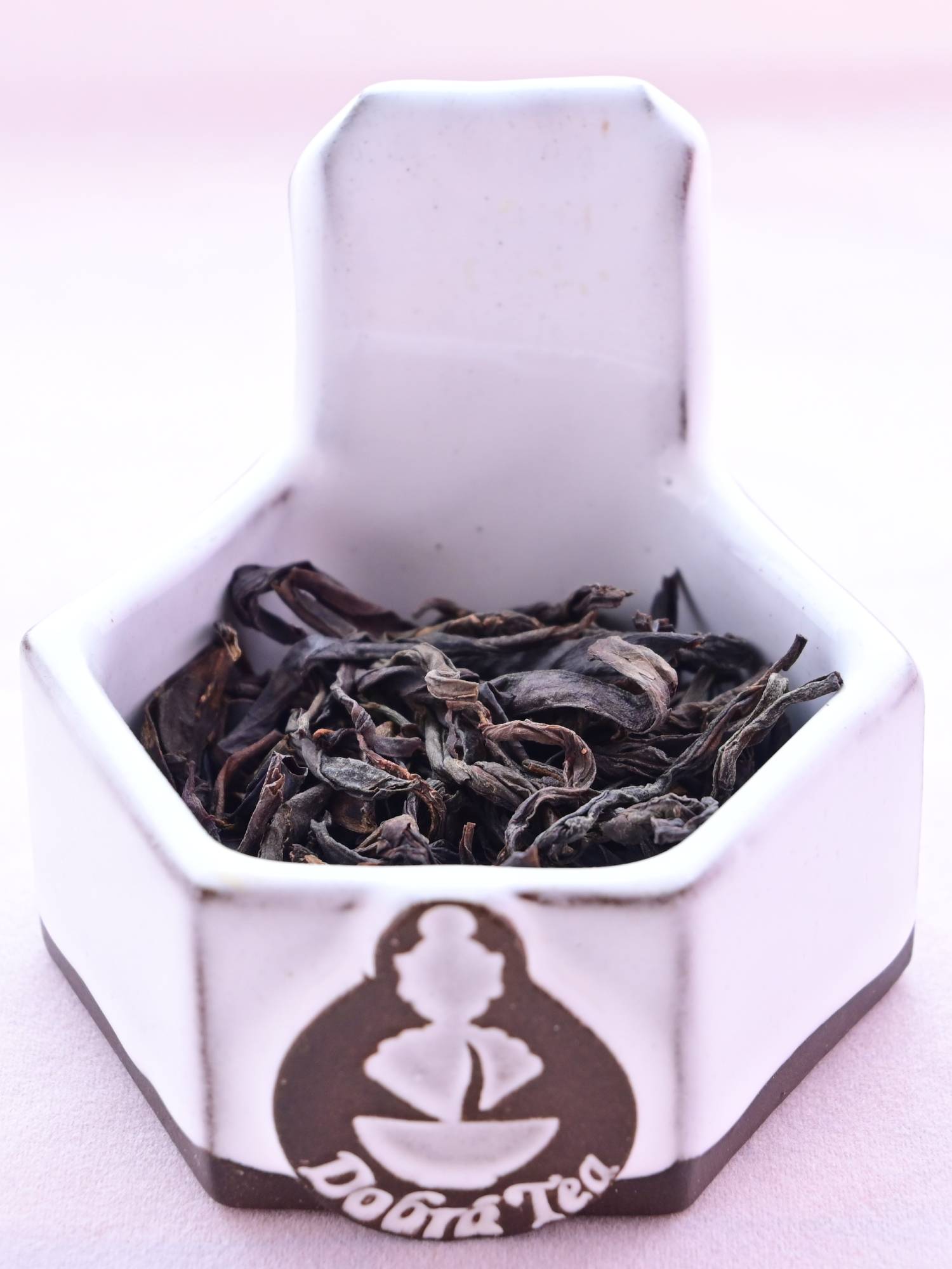 A close-up of Feng Huang Dan Cong leaves. They are dark brown, like cocoa nibs, and have withered into a flat, drooping shape.