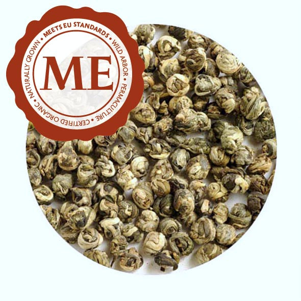 A close-up of tea leaves rolled into compact balls. Each ball is the size of a finger nail, and varies in color from off-white to dark green. A sticker shows that the tea meets EU standards.