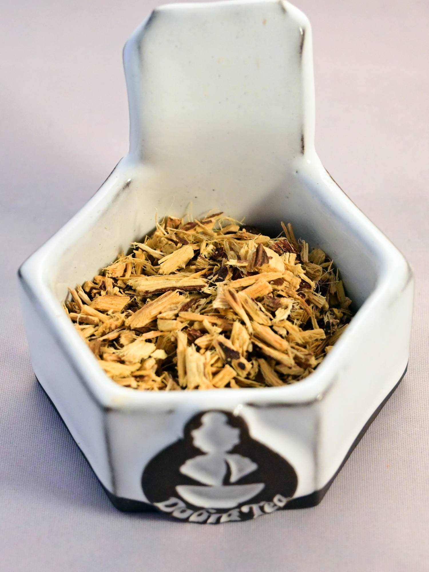 A close-up of dried licorice root. It is soft yellow and fibrous.