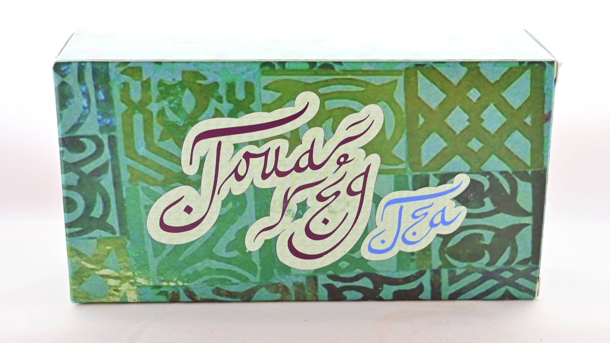 The Touareg box is predominantly green, with Moroccan designs tiled across it. Curly lettering in brown and blue reads "Touareg Tea".