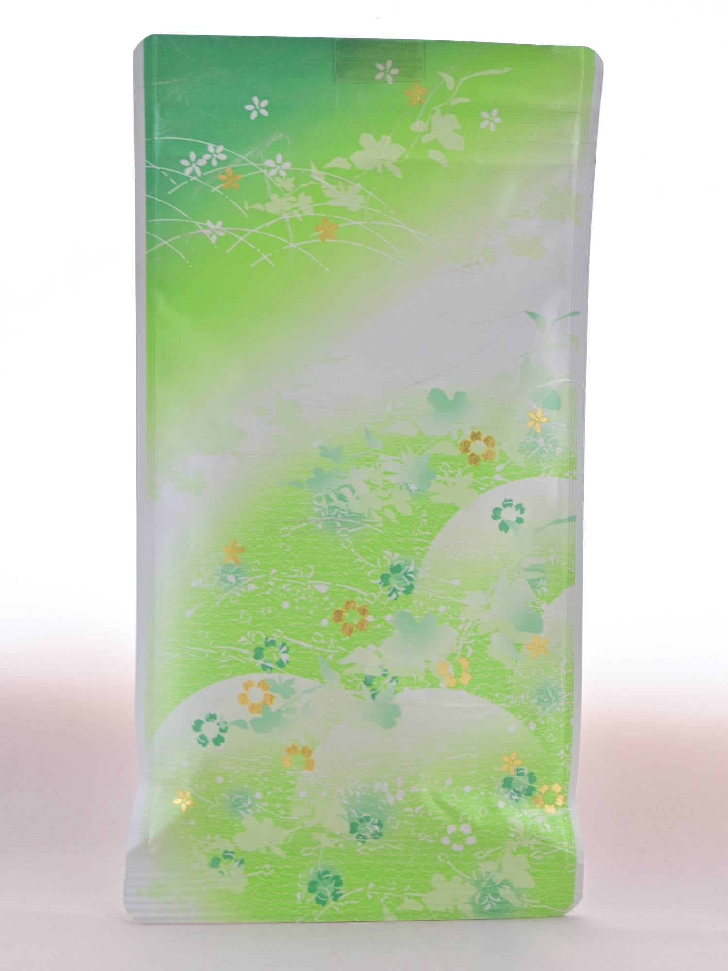 The plastic Yamacha packet is predominantly light green and portrays rolling hills of grass There are flowers in green, white, and gold sprinkled across the package.