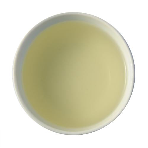 A face-down picture of steeped Long Jing. The steeped tea is a soft, light green-yellow color.