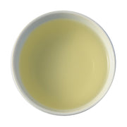 A close-up of steeped Nok Cha tea. The liquid is a rich, creamy yellow.