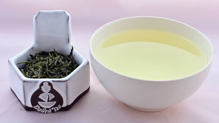 A side-by-side comparison of Bancha leaves and the steeped tea. On the left, the leaves appear dark green and thin. On the right, the steeped tea is a soft yellow.