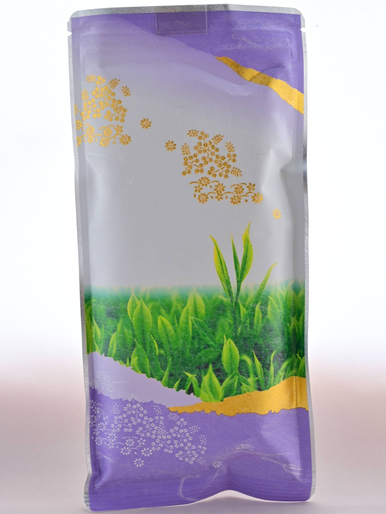 The Bancha packet is primarly purple, with golden-painted mountains and flowers. The image featured in the center of the package is of fresh growth on a tea bush.