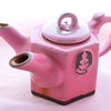 The dual-spouted Casanova rose tea pot is hexagonal and pink in color, with a Dobra Tea logo of exposed brown clay on the side.
