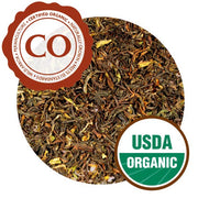 A close-up of Darjeeling Himalaya leaves. They are loosely curled, looking more pressed than previous iterations, and range in color from bright yellow to dark brown. The tea is labeled as Certified Organic and carries a USDA Organic label.