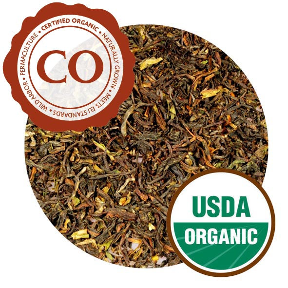 A close-up of Darjeeling Himalaya leaves. They are loosely curled, looking more pressed than previous iterations, and range in color from bright yellow to dark brown. The tea is labeled as Certified Organic and carries a USDA Organic label.