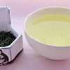 A side-by-side comparison of Gyokuro leaves and steeped tea. On the left, the leaves are long and needle-like, with a rich dark green color. On the right, the steeped tea is a pale green.