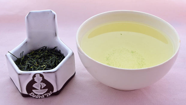 A side-by-side comparison of Gyokuro leaves and steeped tea. On the left, the leaves are long and needle-like, with a rich dark green color. On the right, the steeped tea is a pale green.