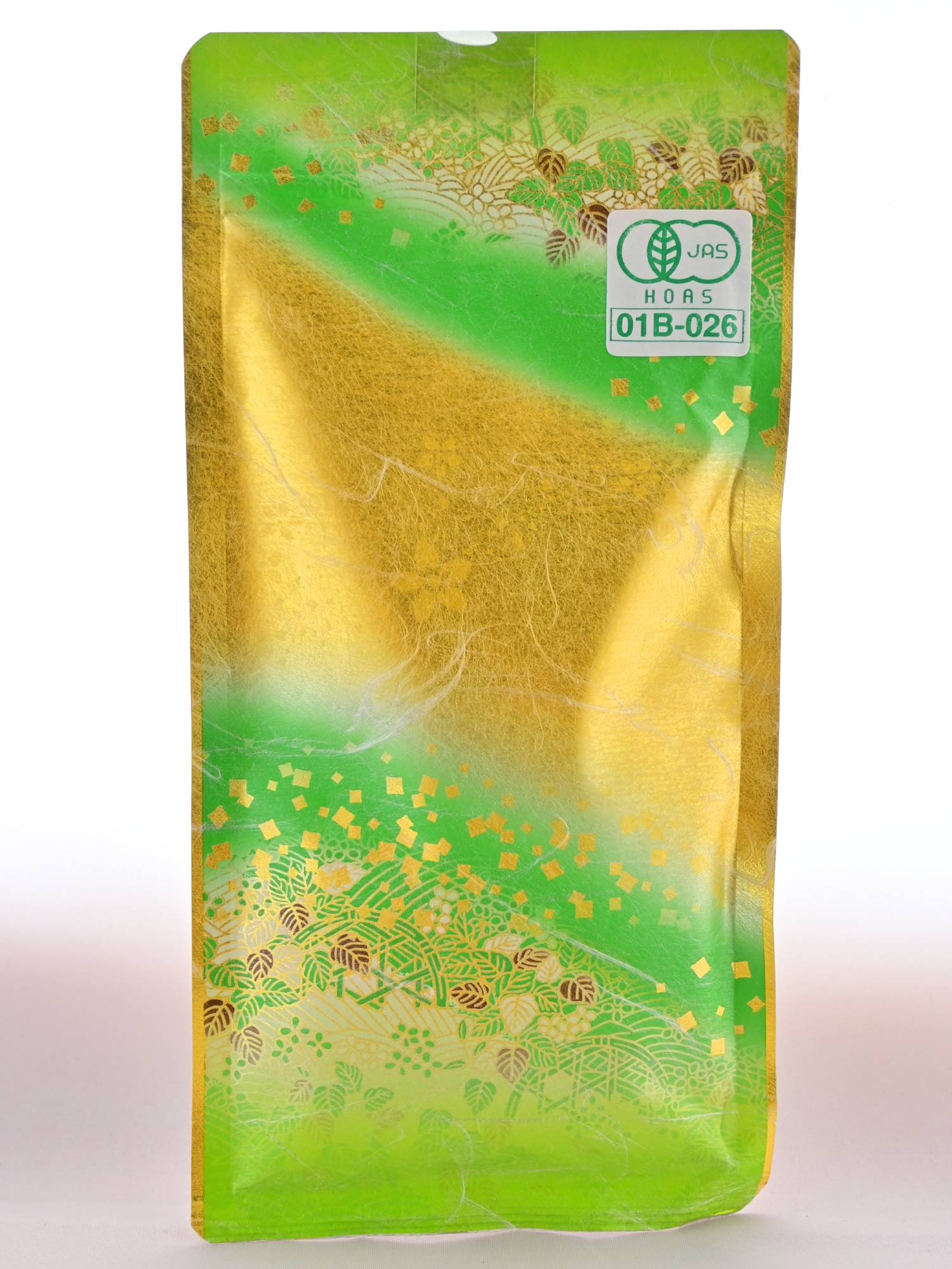 The plastic Gyokuro package is predominantly green, with gold pine tree detailing and a downward angled slash of gold through the middle. In the top right corner is a lot certification sticker.