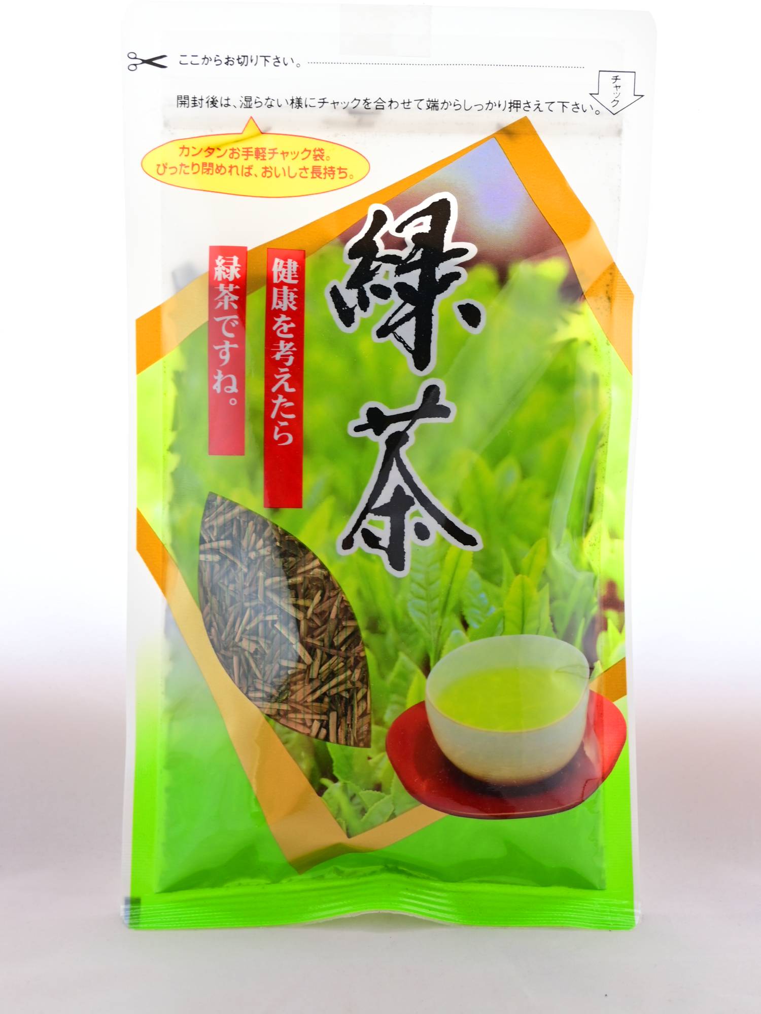 The plastic Hojicha packet prominently features a picture of a growing, green tea bush framed by a diamond in gold. There is a clear spot in the package that shows the stems inside, There are Japanese letters explaining the opening process and resealable nature of the package, as well as the name. 