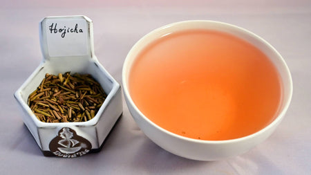 A side-by-side comparison of Hojicha stems and steeped tea. On the left, the roasted stems are short and even in length, and have been roasted to a light brown color. On the right, the steeped liquid is orange.
