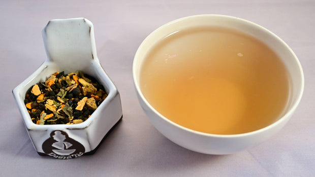 A side-by-side comparison of Immunitea blend and steeped tisane. On the left, the tea blend prominently features elderberries, turmeric, and ginger. On the right, the steeped tisane is a smoky, muted orange.