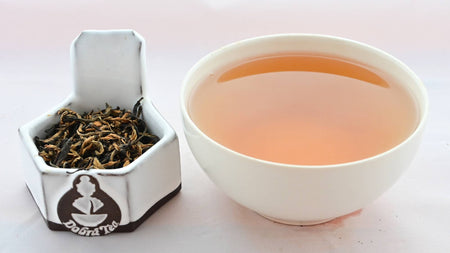 A side-by-side comparison of Jin Zhen leaves and steeped tea. On the left, the leaves are an equal mixture of dark brown and black, and spiral around one another. On the right, the steeped tea is dark orange.