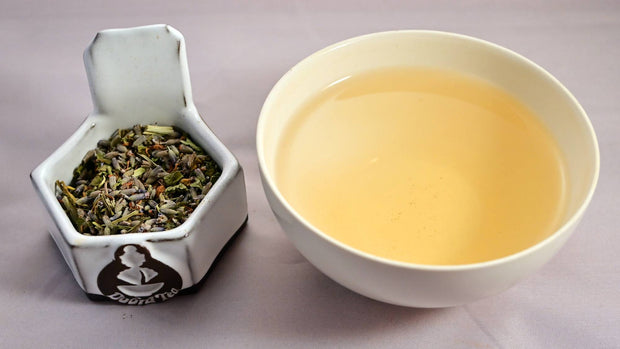 A side-by-side comparison of the Jovialitea blend and steeped tisane. On the left, the blend prominently features lavender and tulsi. On the right, the steeped tisane is a rich yellow color.