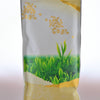 The plastic Kamacha packet has soft gold on the top and bottoms of it, with an image of the tops of tea bushes in the middle. There are golden flower fields and mountains painted along the edges. At the very top is a line of the resealable package closure.