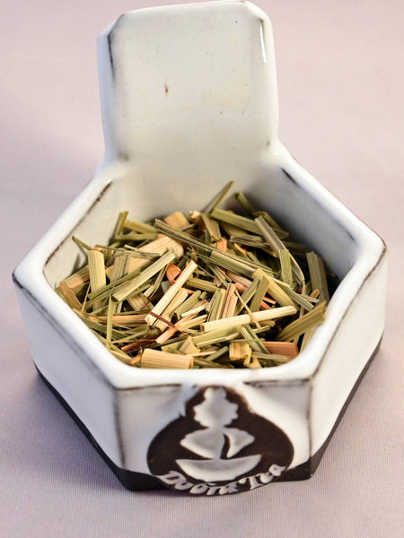 A close-up of lemongrass. It consists of long, flattened tubes ranging in color from muted green to pale yellow.