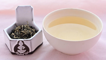 A side-by-side comparison of Magnolia Mao Jian leaves and steeped tea. On the left, the leaves are twisted and range in color from light green to dark green. On the right, the steeped tea is a pale yellow.
