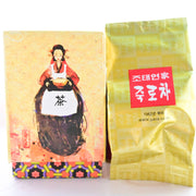 The Nok Cha box on the left features a woman in red and white leaning over a table with Korean letters on it. Inside, displayed on the right of the picture, is a golden plastic bag with Korean letters in red.