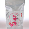 A plastic, resealable package holding Sakuracha. The package is white and has a label depicting flowers and pink Japanese text.