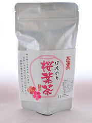 A plastic, resealable package holding Sakuracha. The package is white and has a label depicting flowers and pink Japanese text.