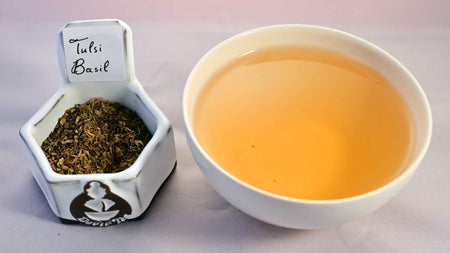 A side-by-side comparison of the tulsi herb and steeped tisane. On the left, the tulsi leaves are small, dust-like and range in color from green to brown. On the right, the steeped tisane is a soft orange color.