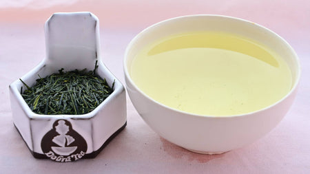 A side-by-side comparison of Yamacha leaves and steeped tea. On the left, the leaves are long, with some being needle-thin and others being relatively flat. They are all dark green. On the right, the steeped tea is a pale green.