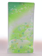 The plastic Yamacha packet is predominantly light green and portrays rolling hills of grass There are flowers in green, white, and gold sprinkled across the package.